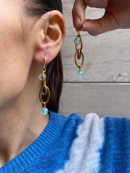 Orecchini con maglie ovali dorate intrecciate e pietre azzurre sfaccettate
